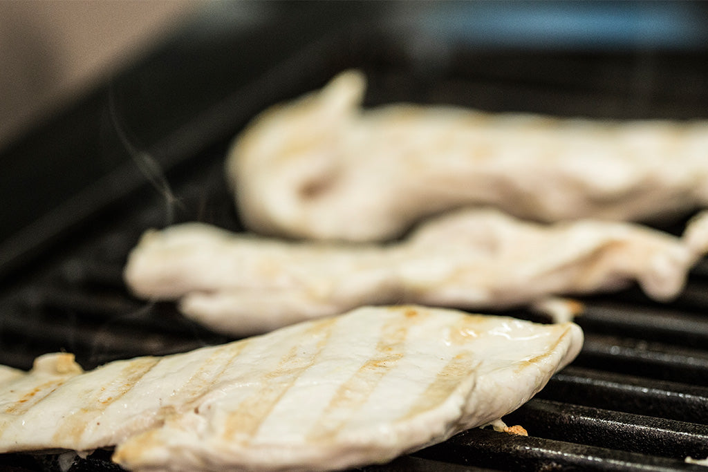 WeGrill Gusseisen-Grillrost im Einsatz mit Hähnchenbrust und Grillstreifen